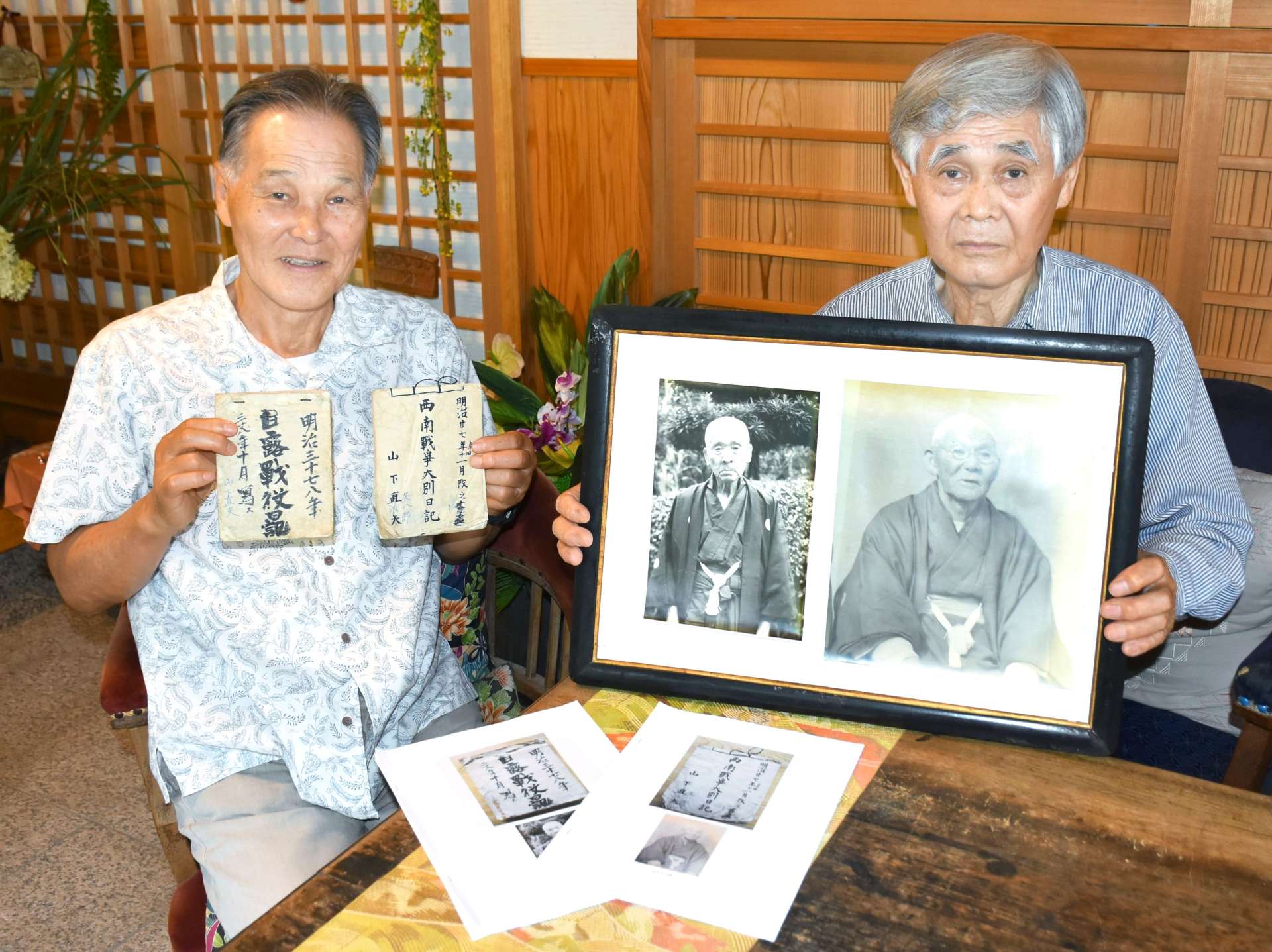 祖父と曽祖父の写真を手にする山下弘文さん（右）と手嶋正次さん＝霧島市横川