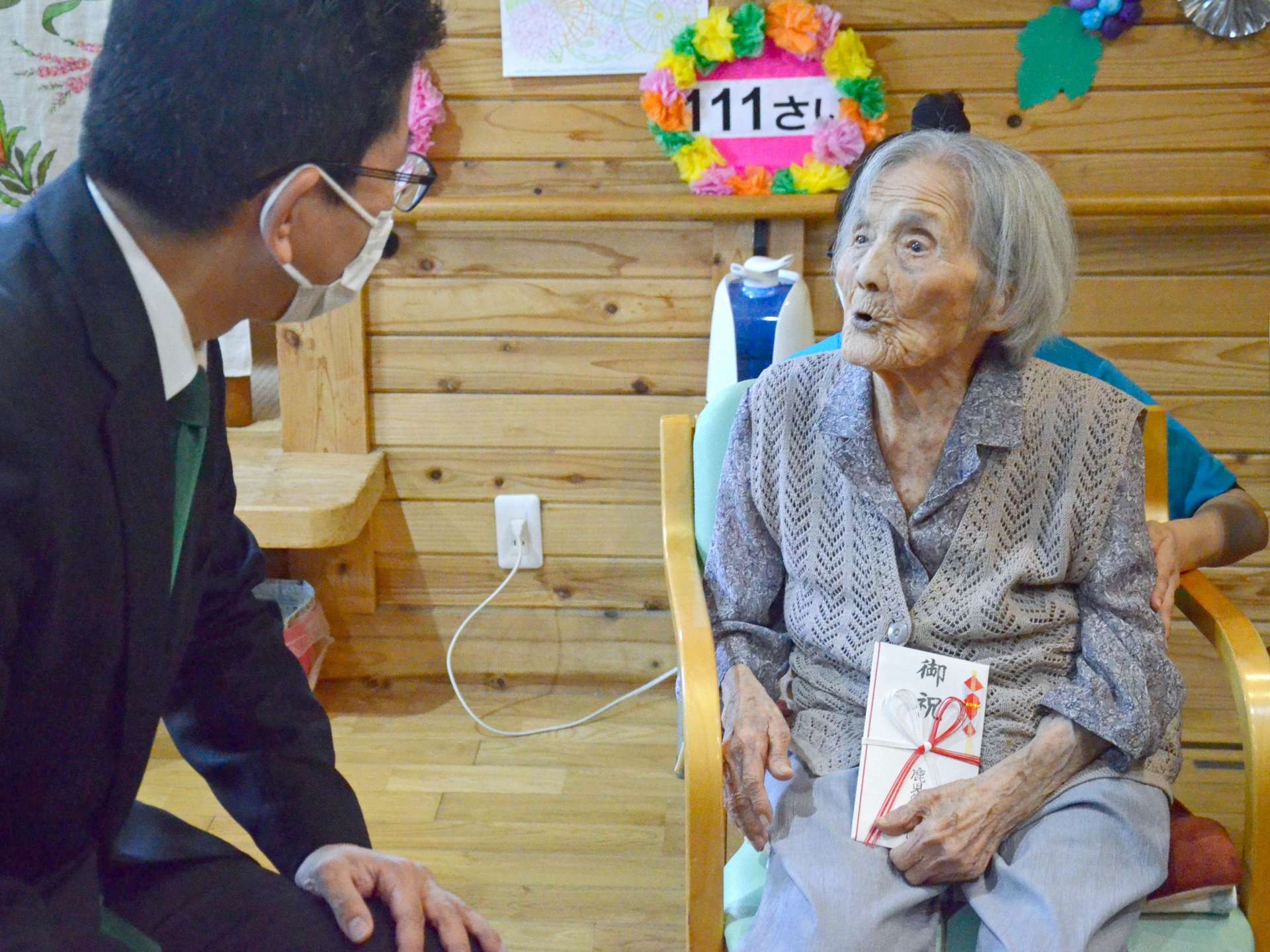 下鶴隆央市長と歓談する県内最高齢の坂下サトさん＝４日、鹿児島市星ケ峯２丁目のデイサービスだんらん