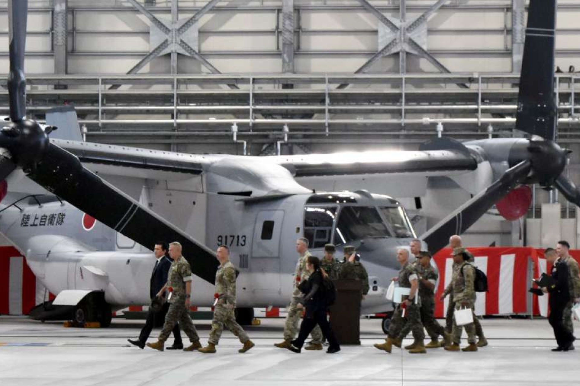 式典会場で陸上自衛隊のオスプレイの前を歩く在日米軍の幹部ら＝７日、佐賀市の佐賀駐屯地