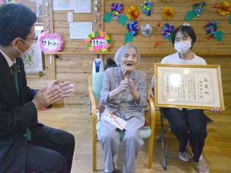 下鶴隆央市長に歌を披露する県内最高齢の坂下サトさん（中央）＝４日、鹿児島市星ケ峯２丁目のデイサービスだんらん