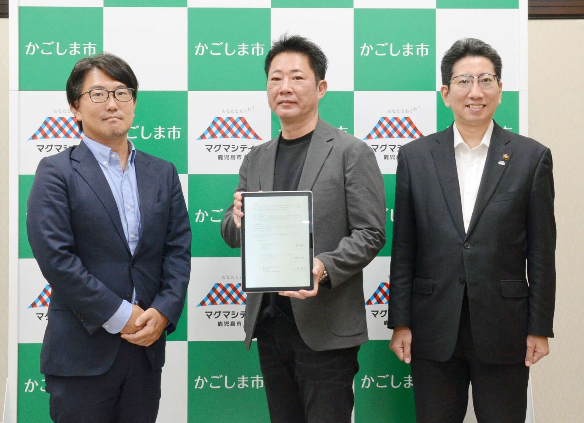 鹿児島市と立地協定を結んだコムテックの伊倉宏英社長（中央）＝４日、同市役所