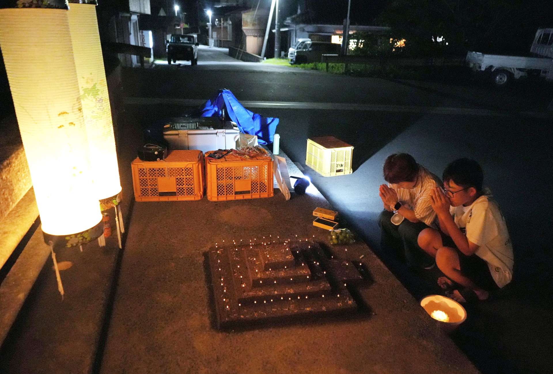 墓石をかたどった砂に線香をあげる牧集落の住民＝８月２７日午後７時５０分ごろ、垂水市本城