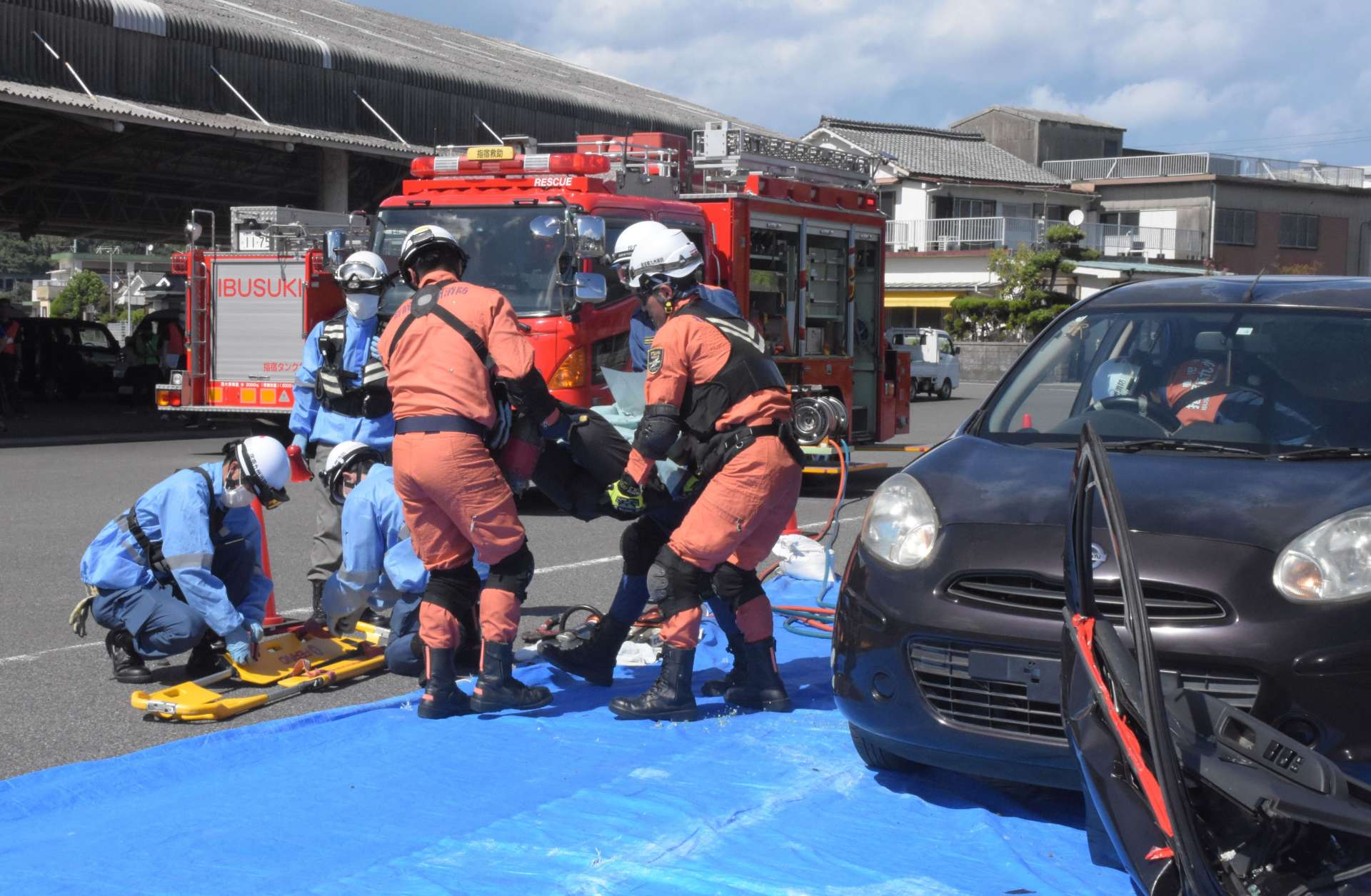 車内に人が閉じ込められた想定で、救助訓練をする参加者＝指宿市の山川漁港