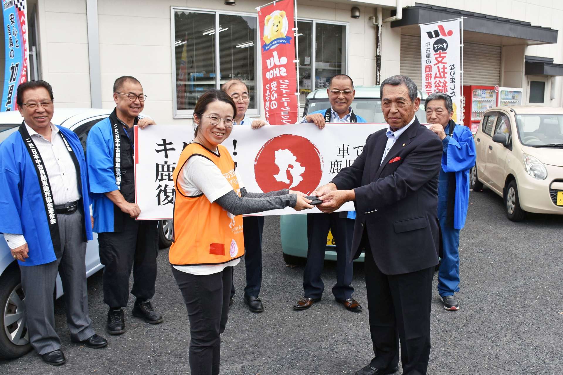 寄贈車両の前でキーを渡すＪＵ鹿児島の新園康男理事長（右）＝１２日、姶良市加治木