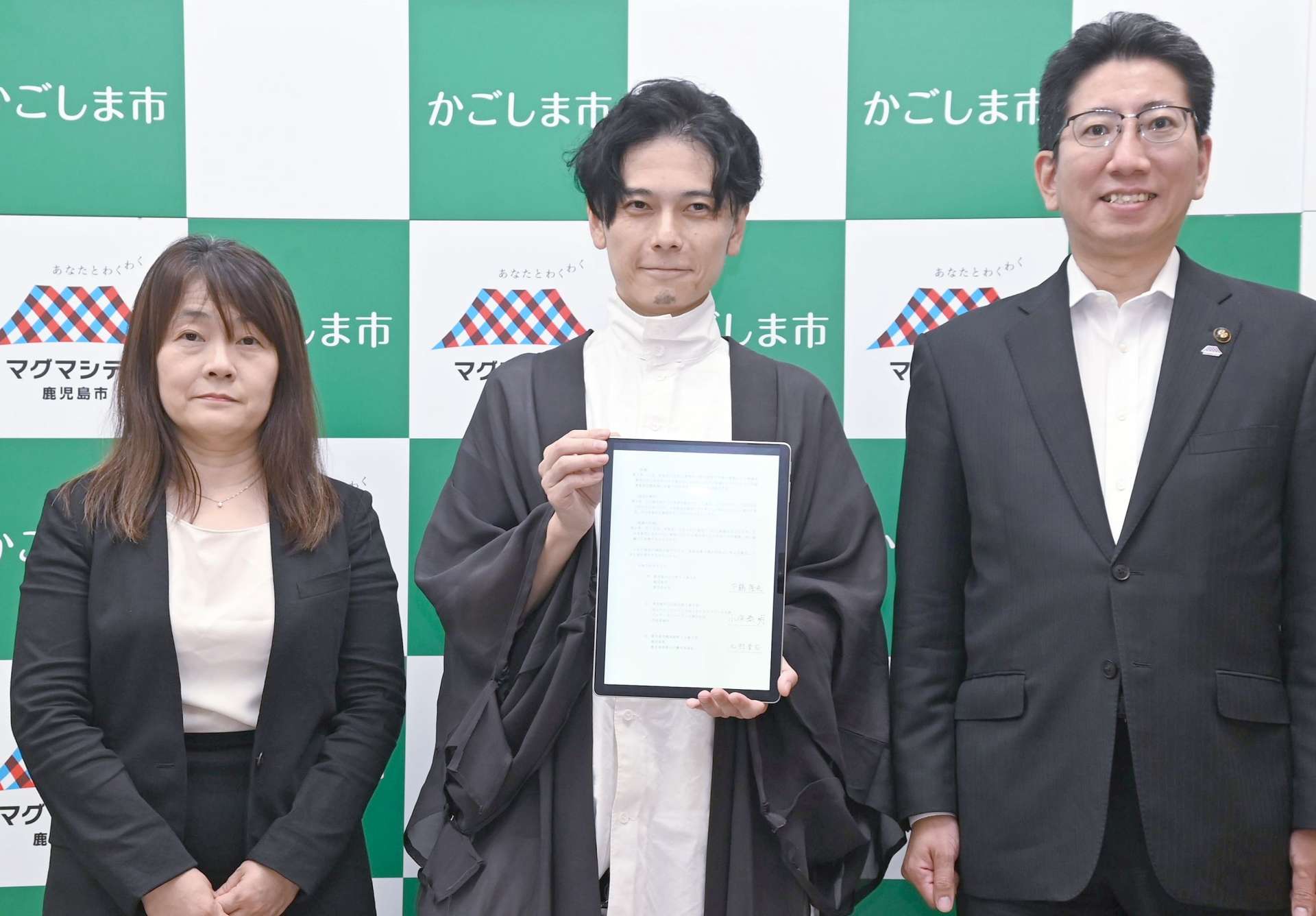 鹿児島市と立地協定を結んだアルサーガパートナーズの小俣泰明社長（中央）＝鹿児島市役所