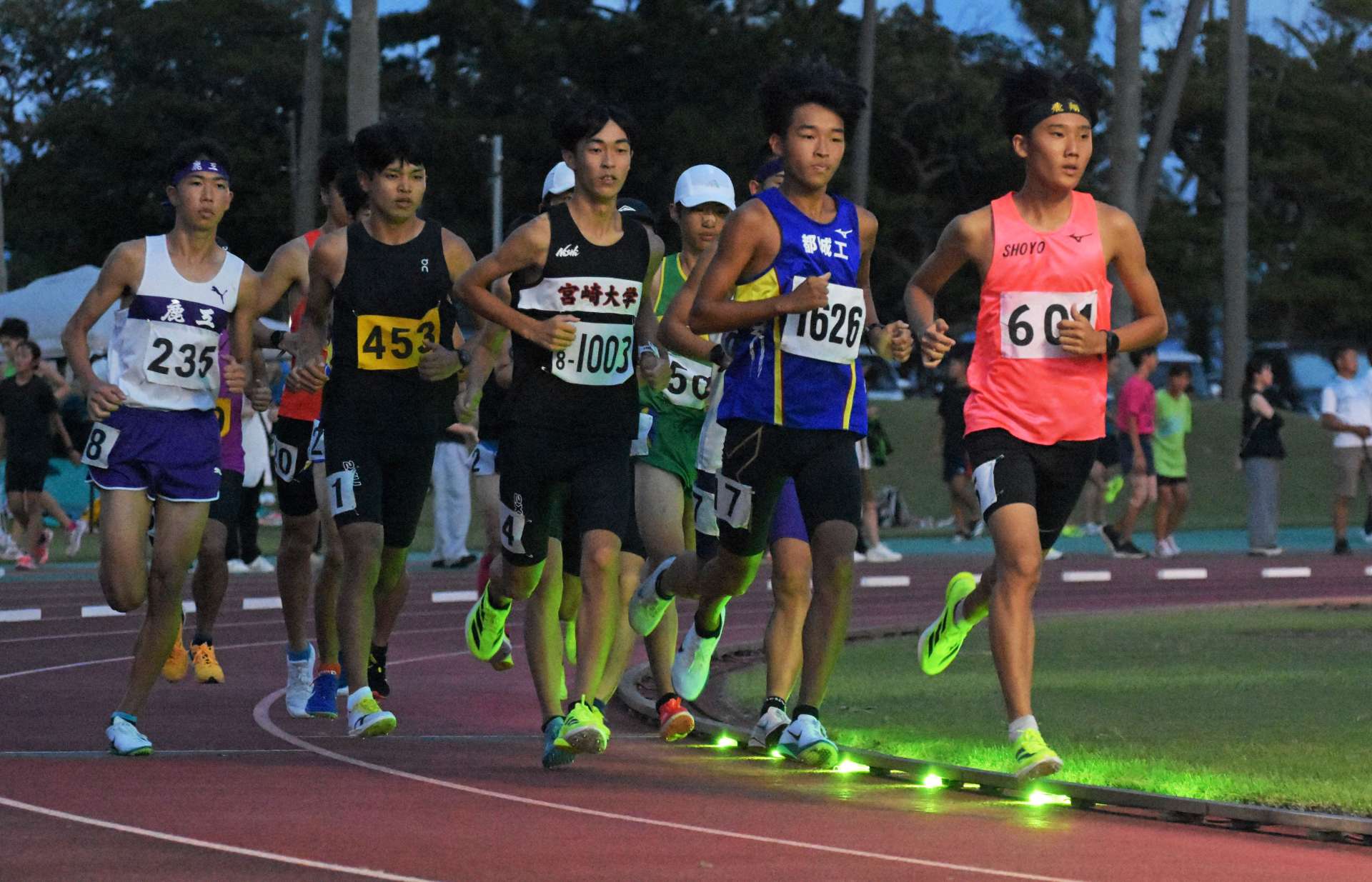 足元の光を目印に、力走する選手たち＝指宿市営陸上競技場