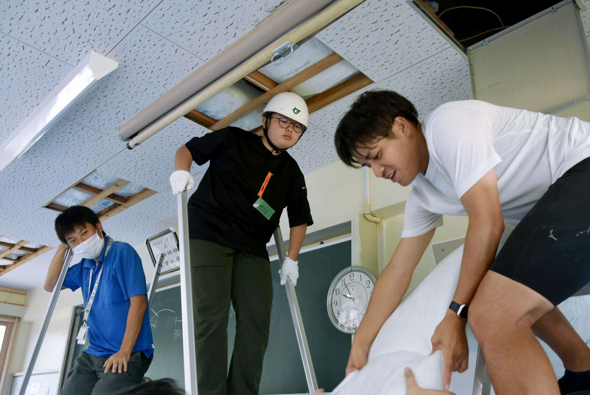 天井に断熱材を設置する中学生ら＝錦江町の田代中学校