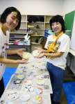 子どもたちが作ったモザイクタイルを手にするウラベメグミさん（左）、裏邉彩子さん＝阿久根市中央公民館鶴見分館
