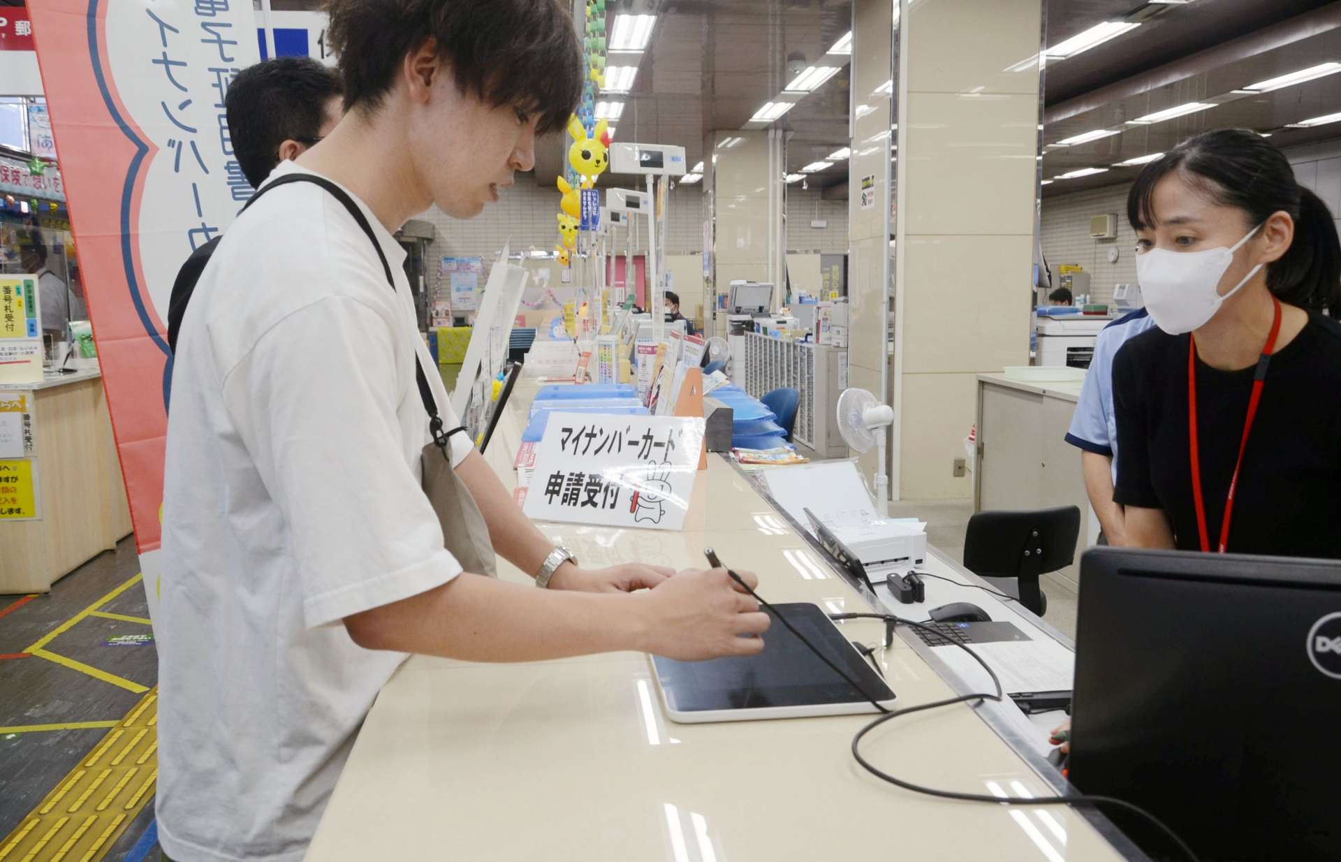 マイナンバーカード電子証明書発行手続きのデモンストレーションをする鹿児島市職員＝同市中央町の中央郵便局