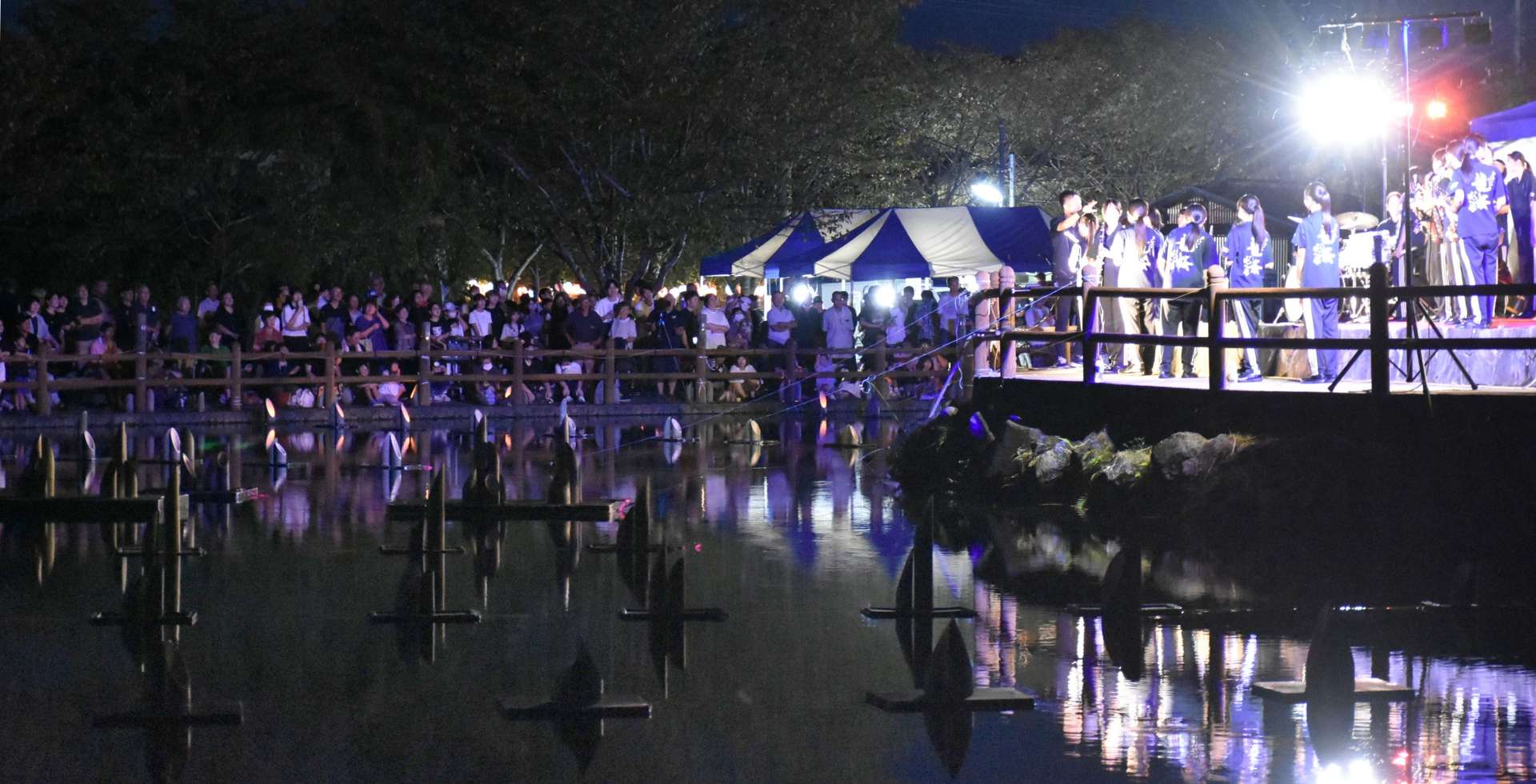竹灯籠の明かりの中、吹奏楽などが演奏されるステージ＝湧水町の丸池公園
