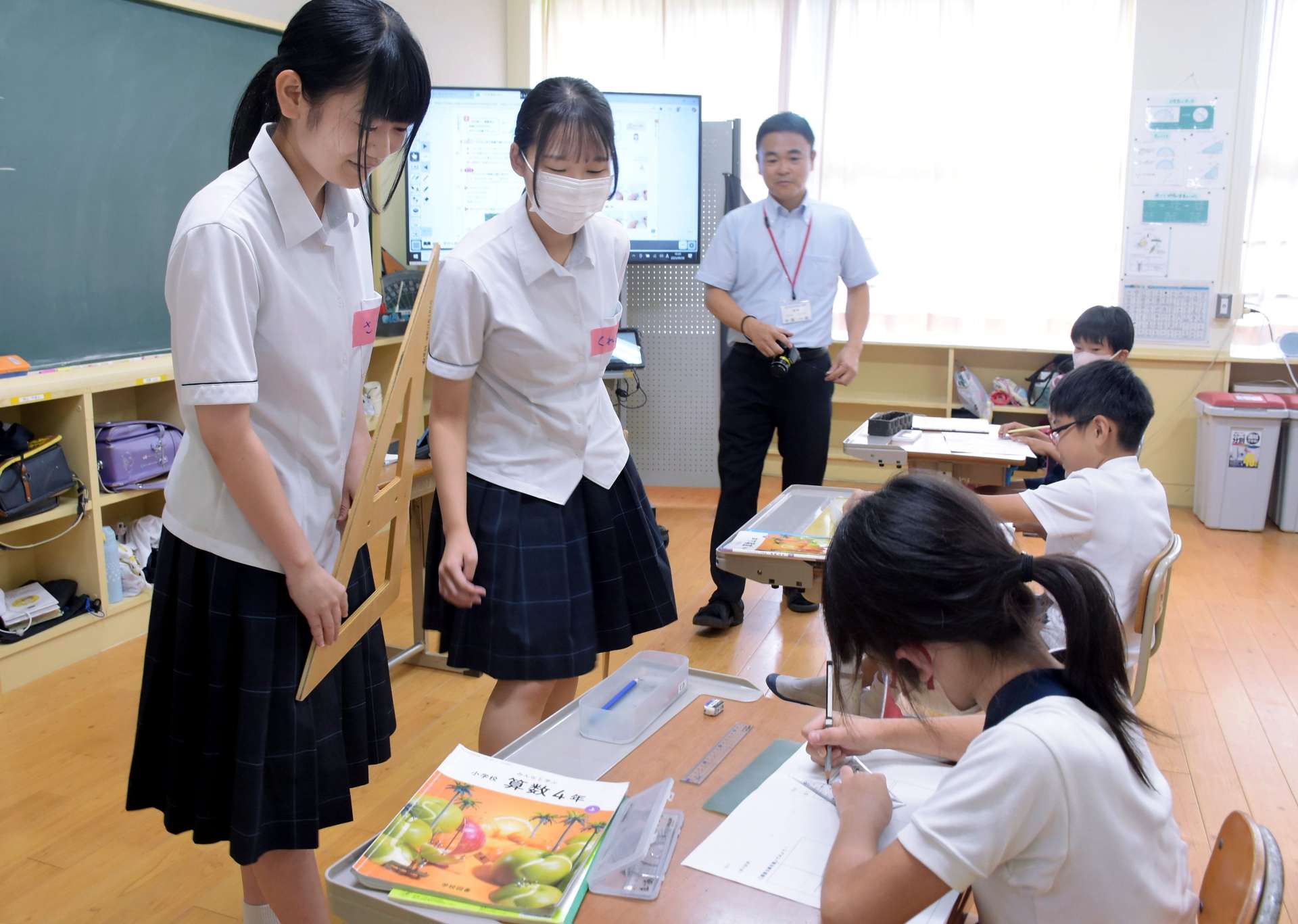 三角定規を使った平行線の引き方を教える志布志高校の生徒＝志布志市の森山小