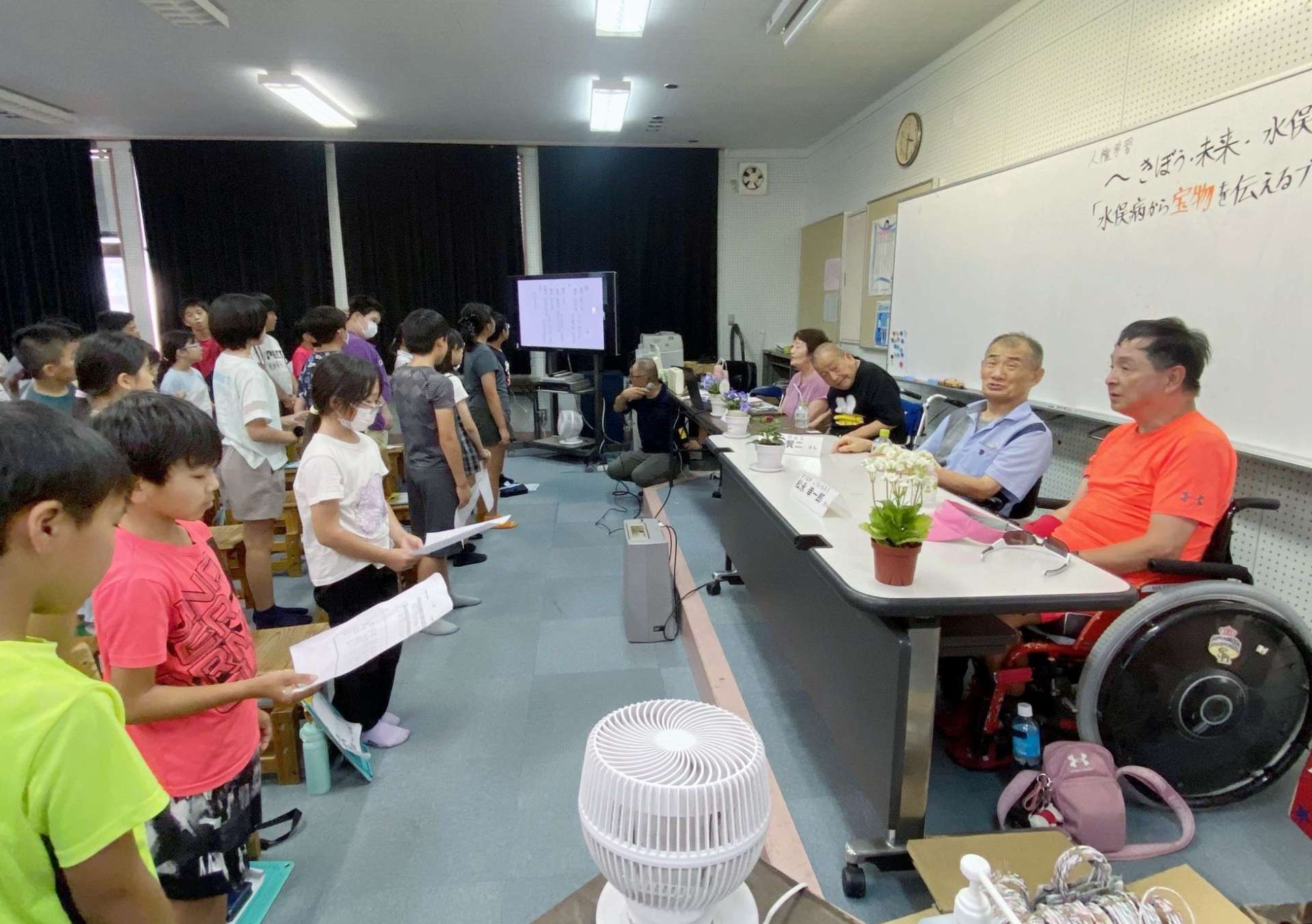 水俣病患者とともに歌を歌う高尾野小学校の児童ら＝出水市