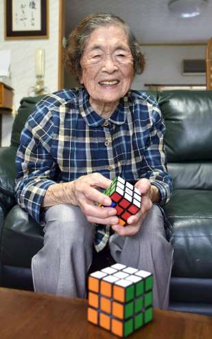 〈関連〉ルービックキューブを手に笑顔を見せる井尻トミエさん＝姶良市北山