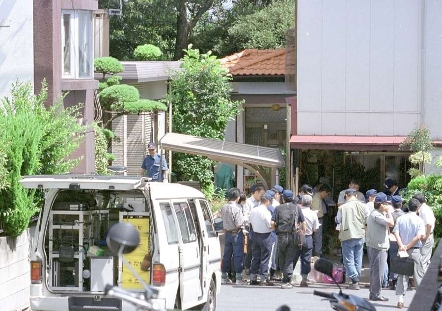 〈事件発覚直後の写真〉遺体搬出後、現場で打ち合わせをする捜査員ら（左奥が被害女性宅）＝２０００年９月１７日午後０時半すぎ、鹿児島市田上台４丁目