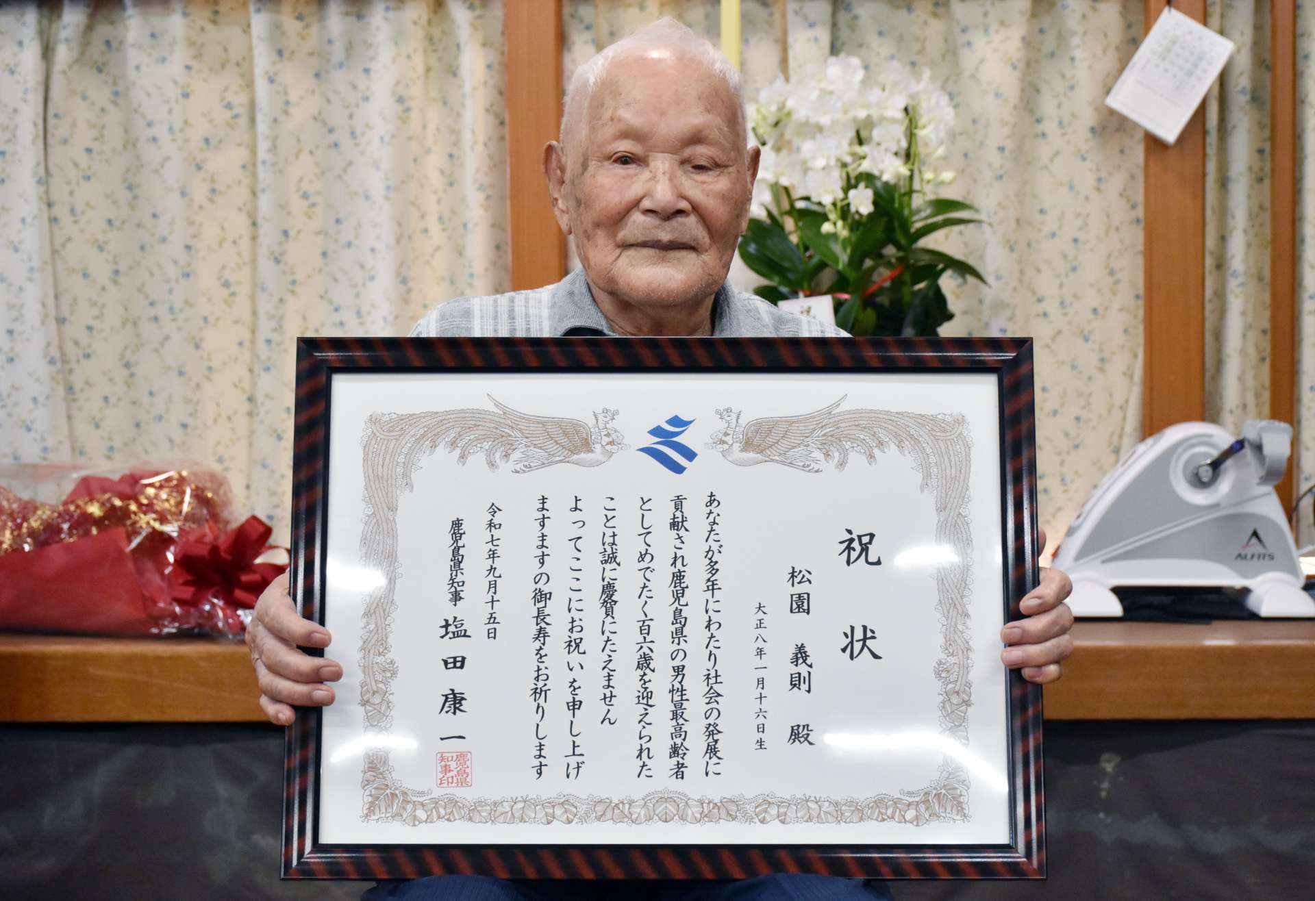 塩田康一知事から祝い状を受け取った県内最高齢男性の松園義則さん＝１５日、鹿屋市浜田町