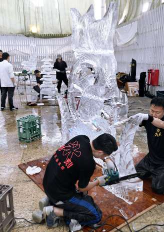 〈別カット〉電動工具で氷の彫刻を仕上げる参加者＝１７日、鹿児島市の天文館ベルク広場