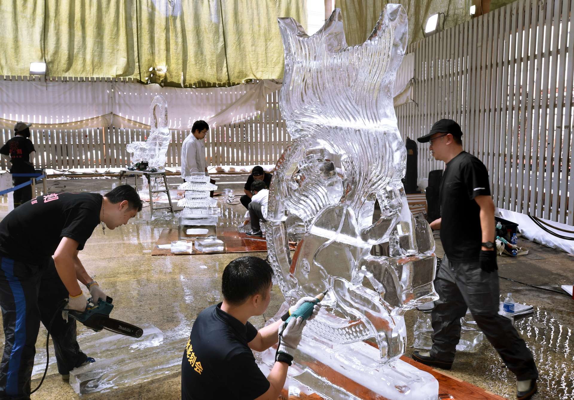 電動工具を使い、氷の彫刻を仕上げる参加者＝１７日、鹿児島市の天文館ベルク広場