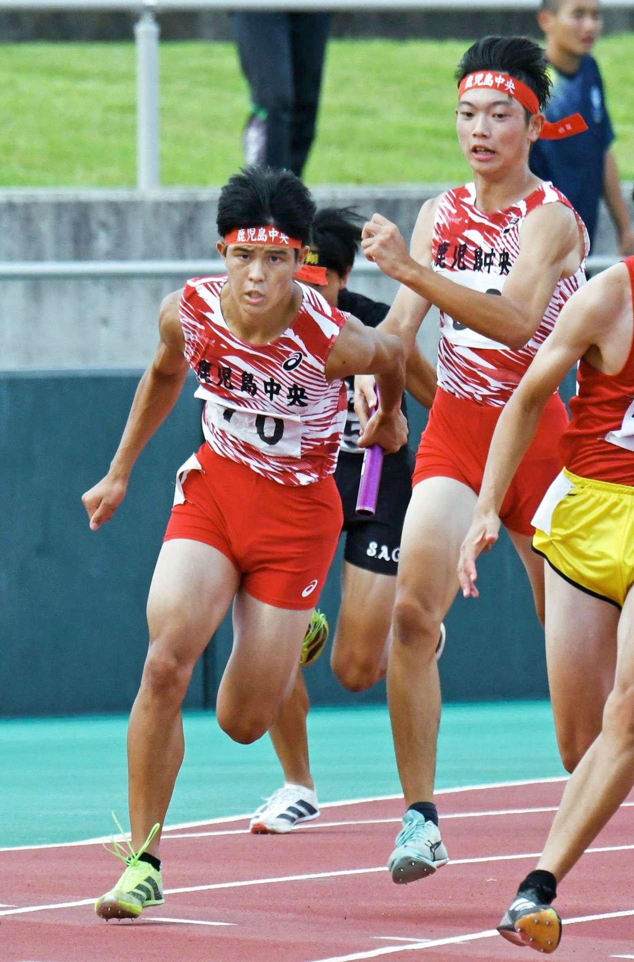 男子４００メートルリレーを制した鹿中央（左）。３走吉留（右）からアンカー井上へバトンが渡る＝白波スタジアム