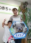 母カナエの背中でエイトが見守る中、記念撮影する名付け親代表のの有川美咲さんと長男英杜さん＝鹿児島市の平川動物公園