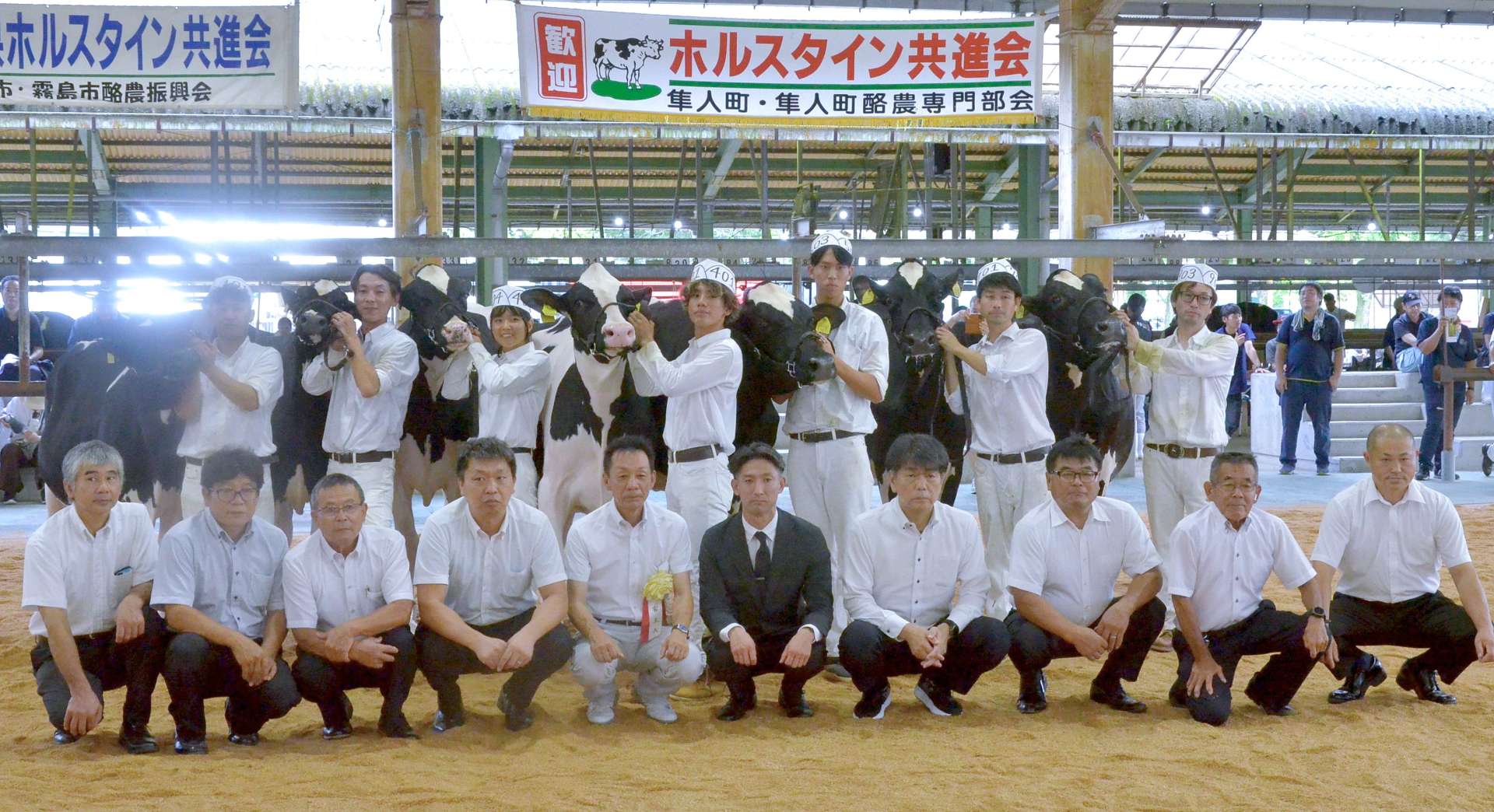 １０月下旬の全日本ホルスタイン共進会北海道大会に向け、県出品牛に決まった７頭と関係者ら＝２０日、霧島市の姶良中央家畜市場