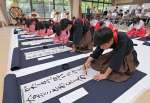 国際平和デーに合わせ、揮毫する樟南高校書道部員＝２１日、鹿児島市の県護国神社
