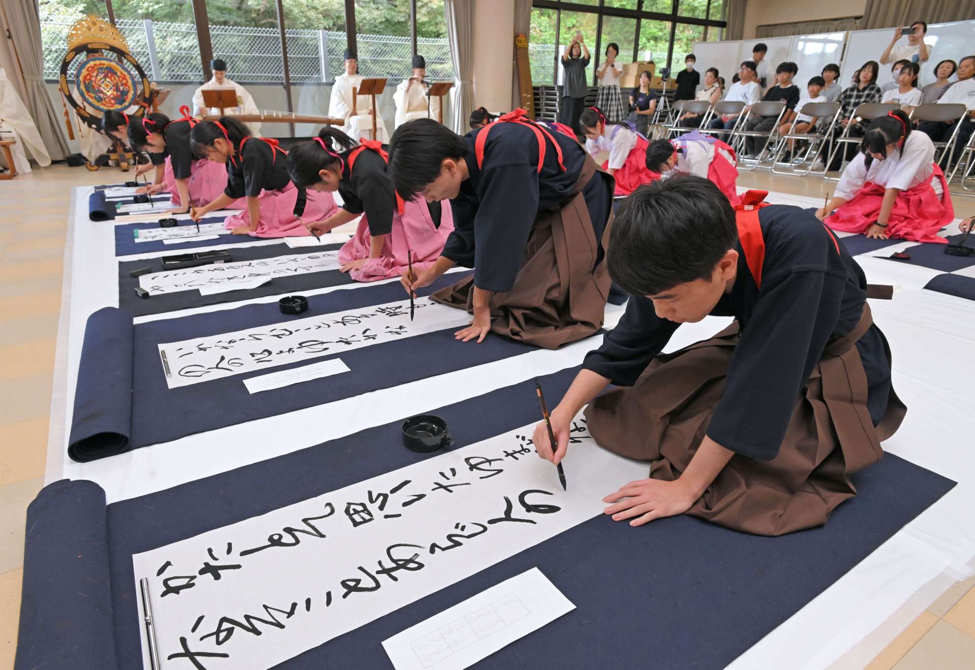 国際平和デーに合わせ、揮毫する樟南高校書道部員＝２１日、鹿児島市の県護国神社