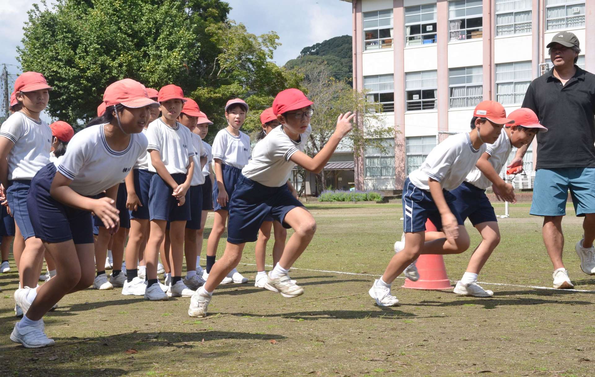 元陸上選手の稲垣誠司さん（右）から走り方のこつを教わる児童＝霧島市横川町中ノの横川小学校