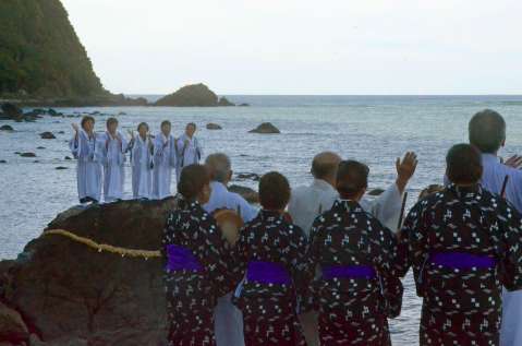 〈関連＝こちらは海岸で〉海辺の岩の上で歌い踊る平瀬マンカイ＝２４日午後４時９分、龍郷町秋名