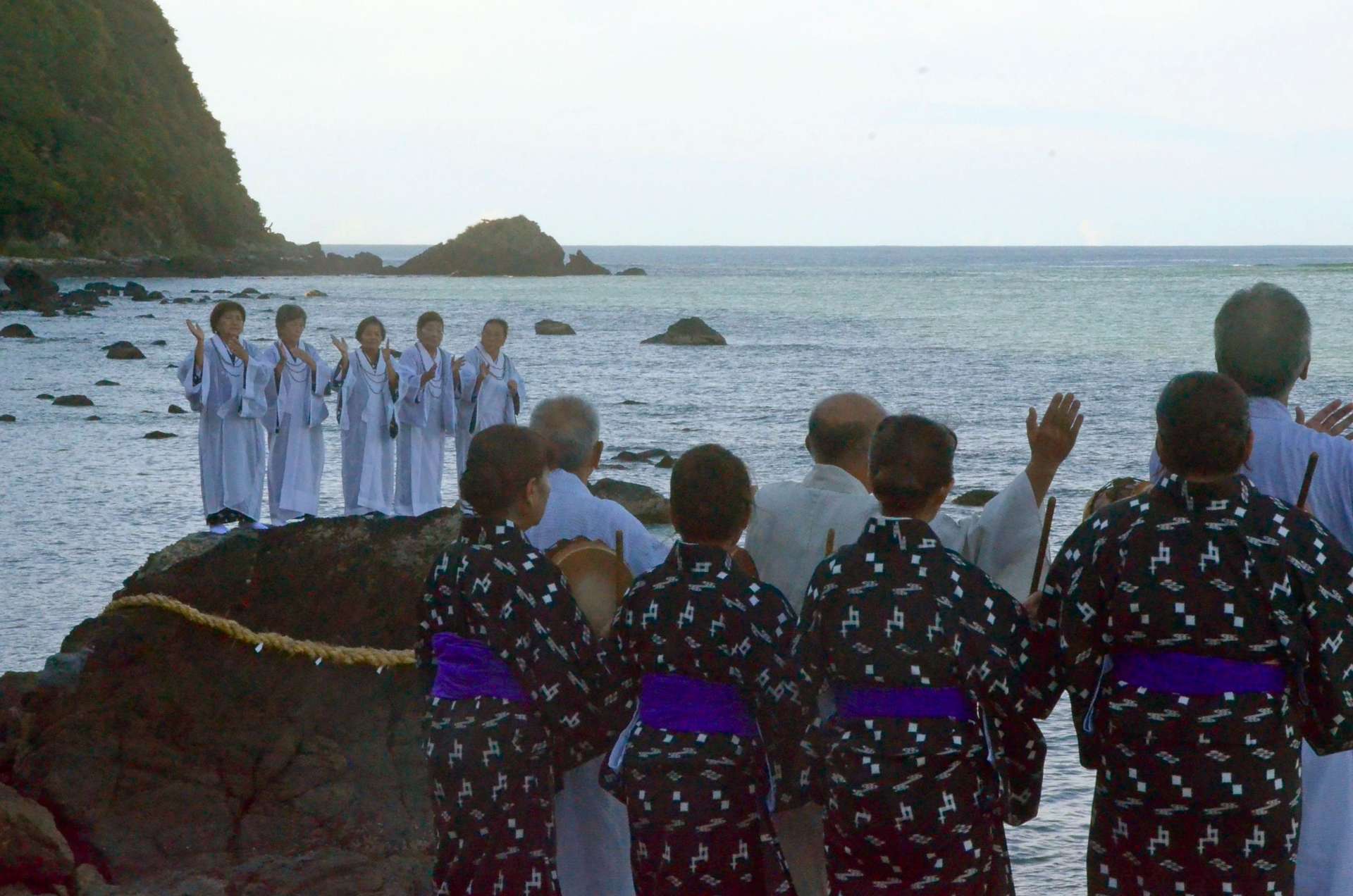 〈関連＝こちらは海岸で〉海辺の岩の上で歌い踊る平瀬マンカイ＝２４日午後４時９分、龍郷町秋名