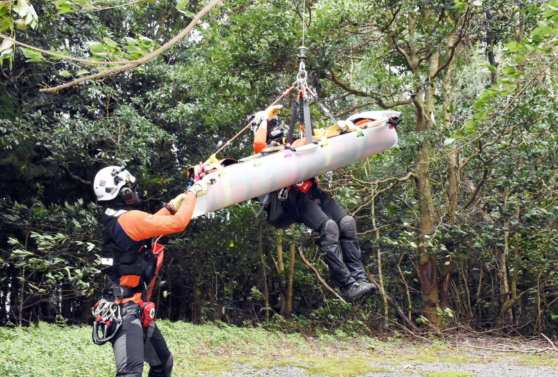 訓練で担架に収容した救助者とヘリにつり上げられる航空隊員＝出水市の矢筈岳中腹