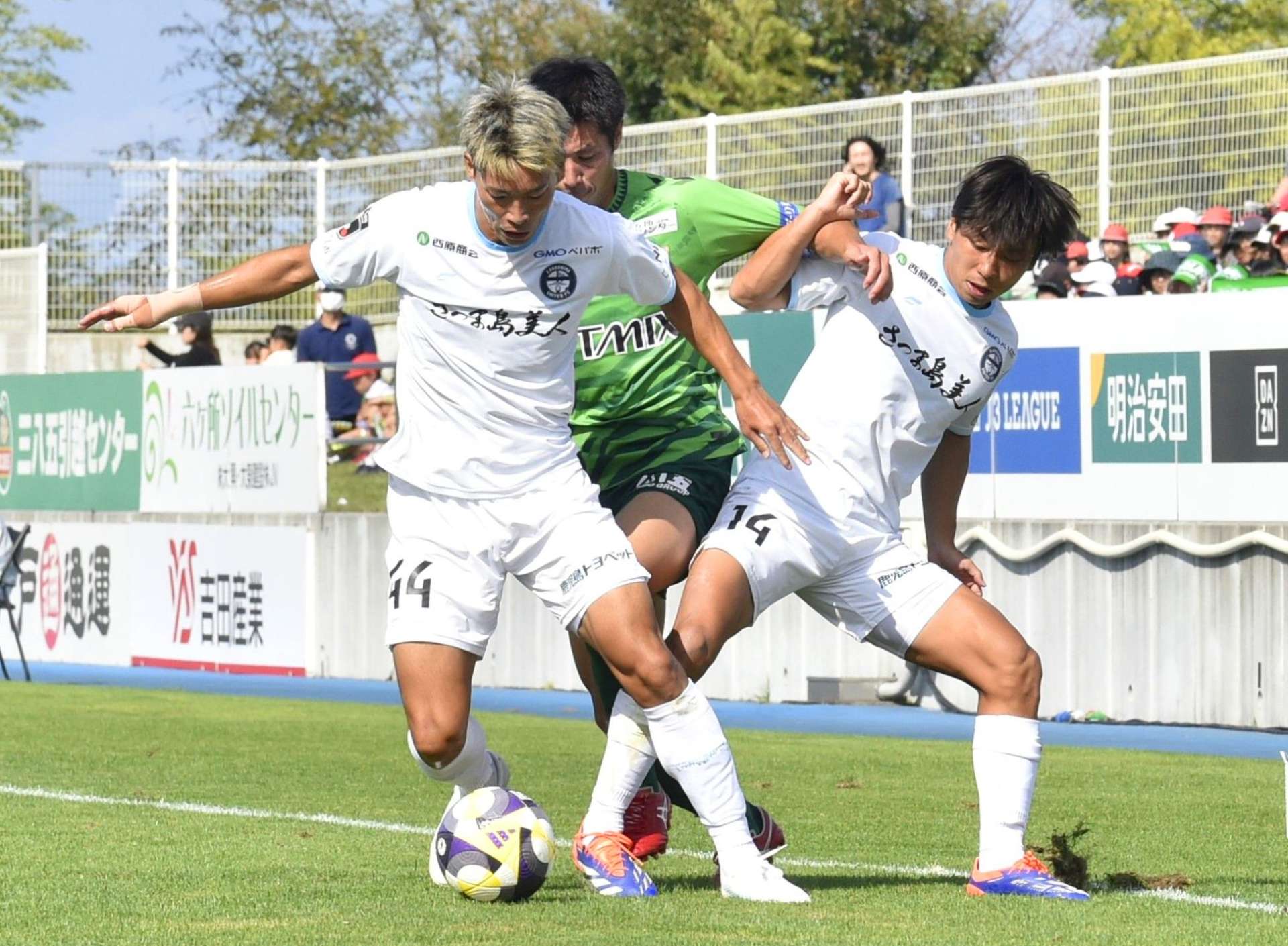 体を張ってボールを奪う鹿児島ＵのＤＦ青木とＭＦ吉尾（右）＝プライフーズスタジアム