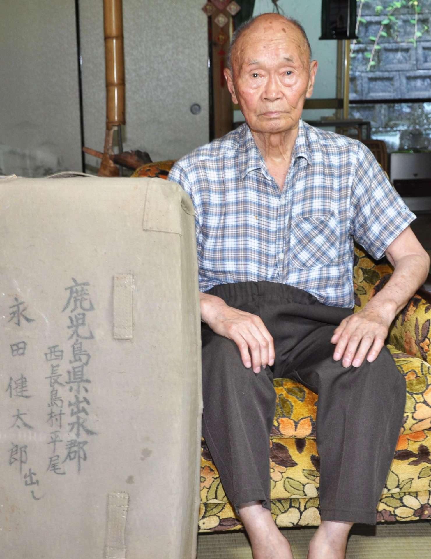 中国での戦闘体験などを語る永田健太郎さん。左手前は出征の際にそろえた将校行李（こうり）＝長島町平尾