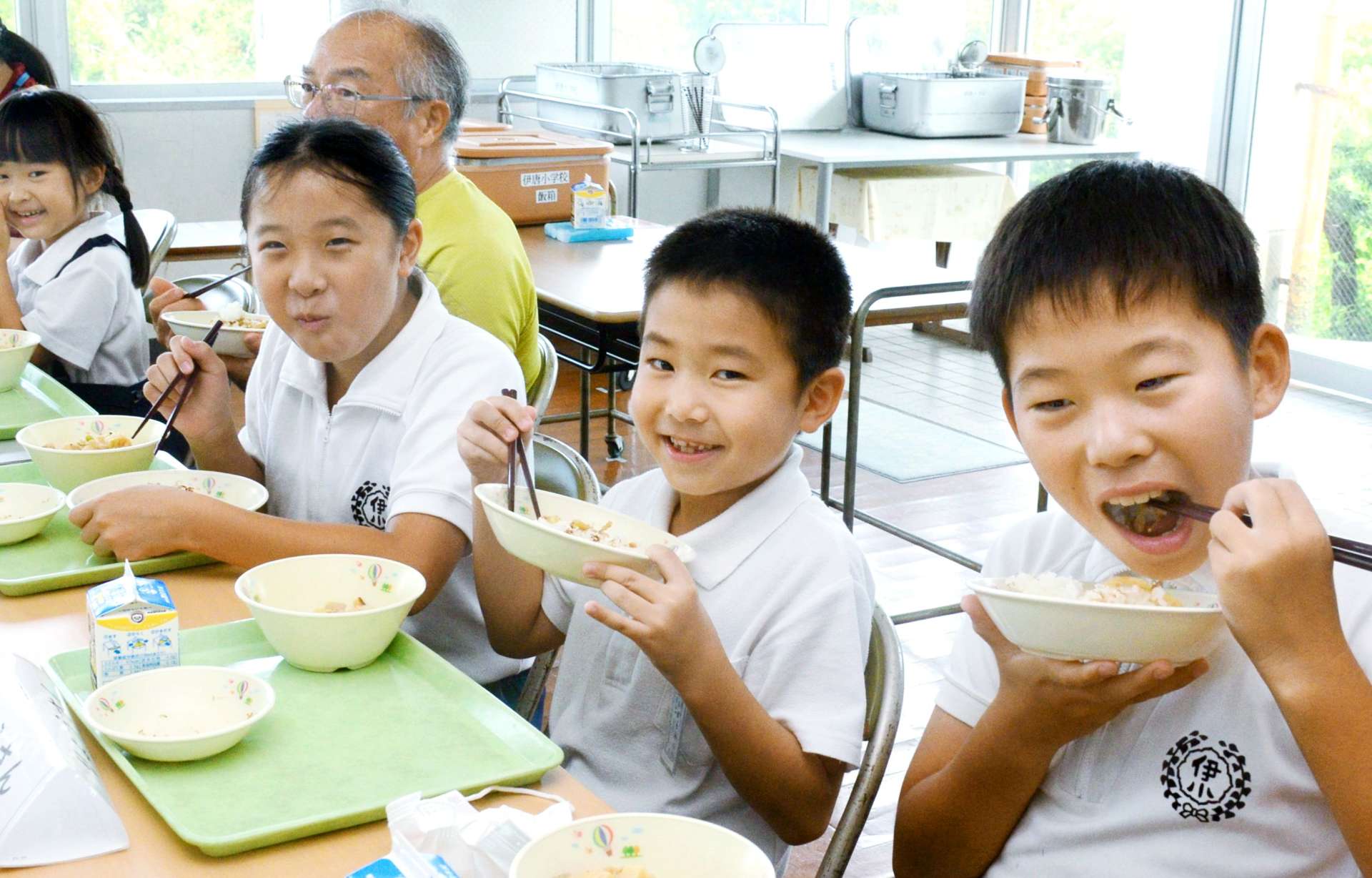 給食の時間に地元産新米を頬張る子どもたち＝長島町の伊唐小学校