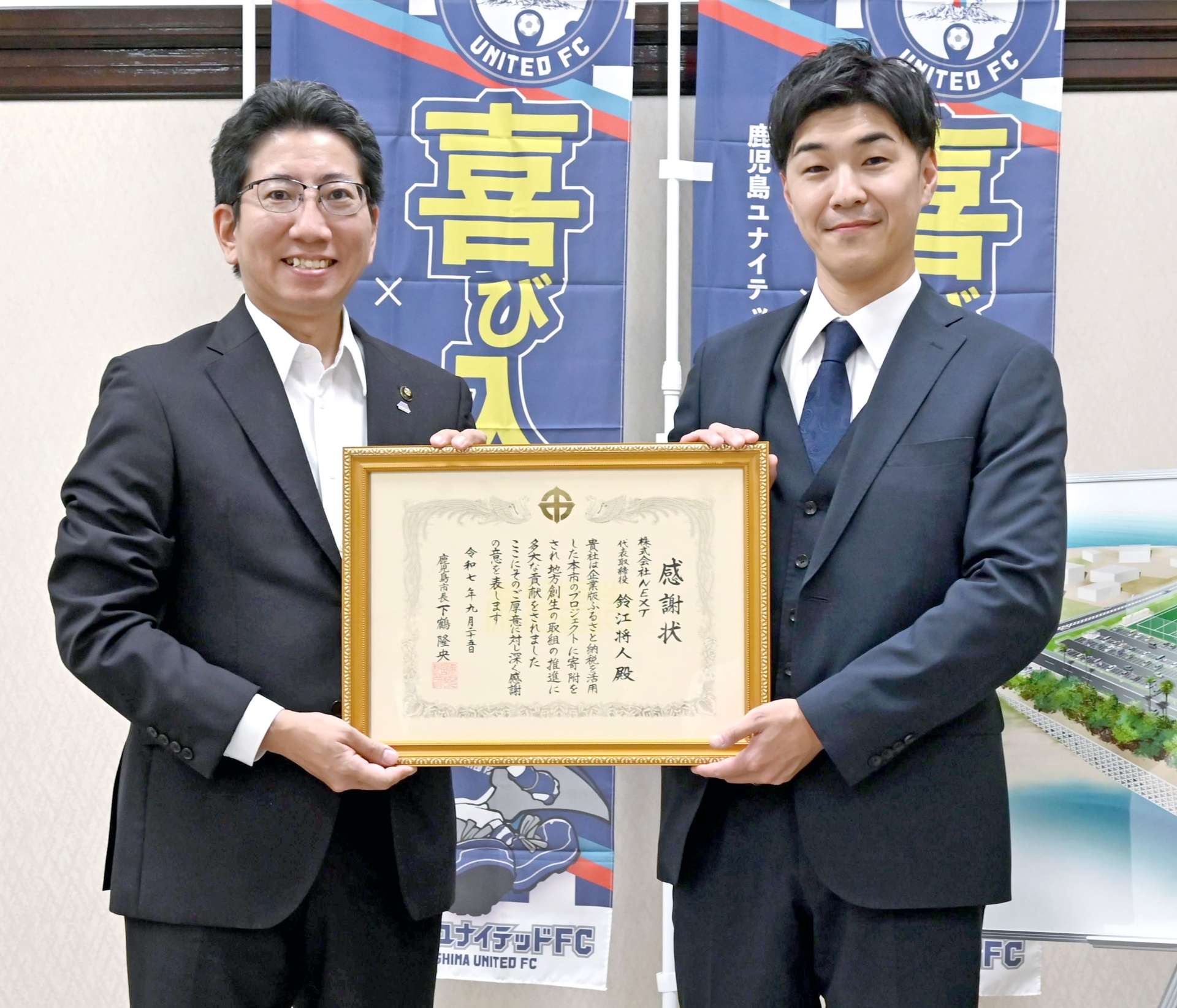 企業版ふるさと納税で感謝状を受ける鈴江将人社長（右）＝２５日、鹿児島市役所