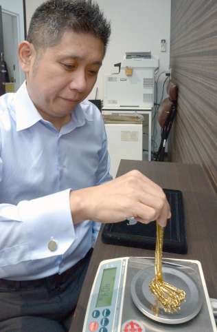 金の重さを量るスタッフ＝２９日、鹿児島市の質屋アシスト宇宿店