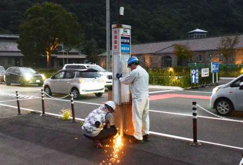 【移設前の現場】旧仙巌園駅前のバス停標識を撤去する作業員＝８月２８日、鹿児島市吉野町