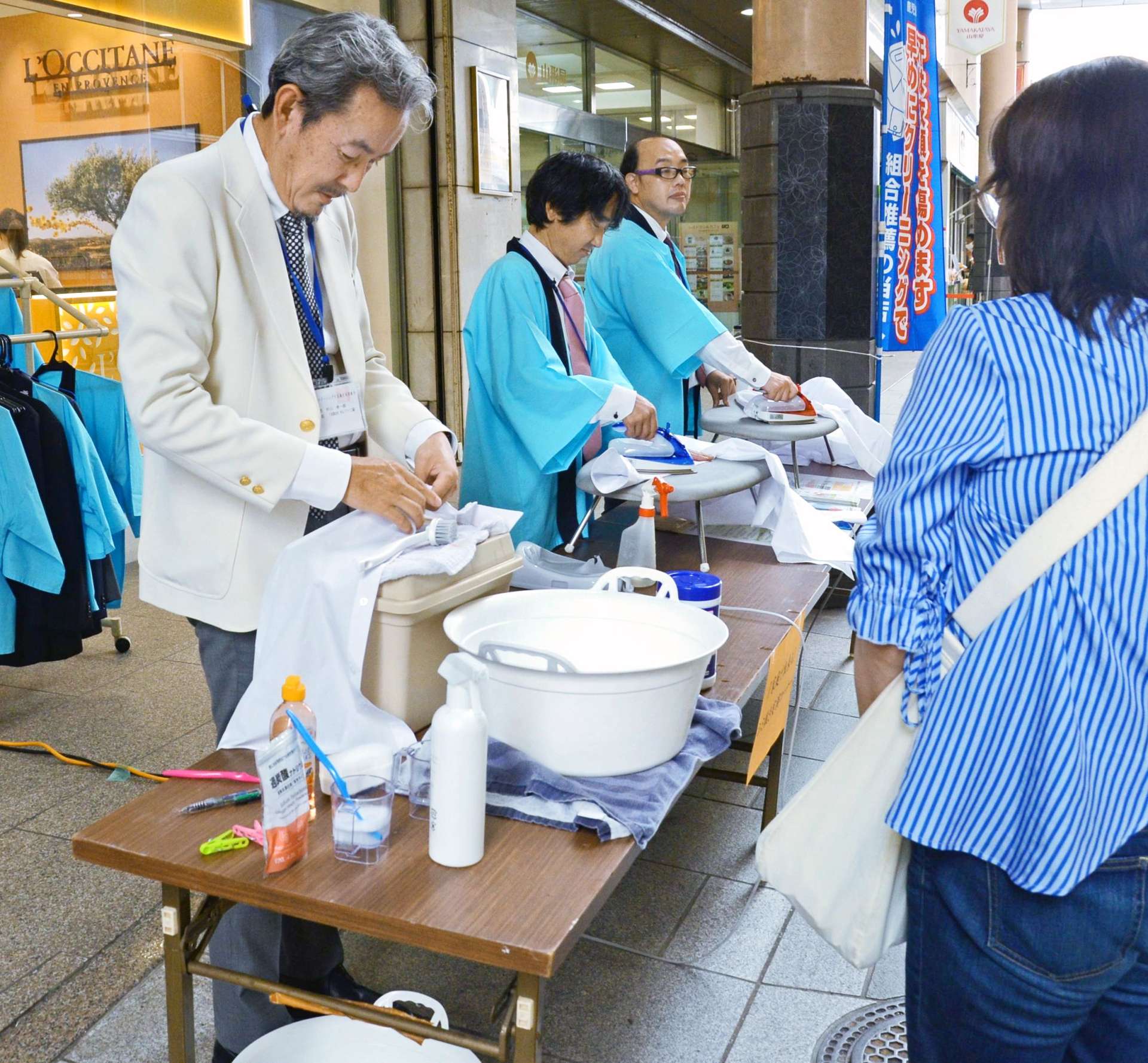 ワイシャツのしみ抜きやアイロン掛けを実演する組合員ら＝２８日、鹿児島市金生町