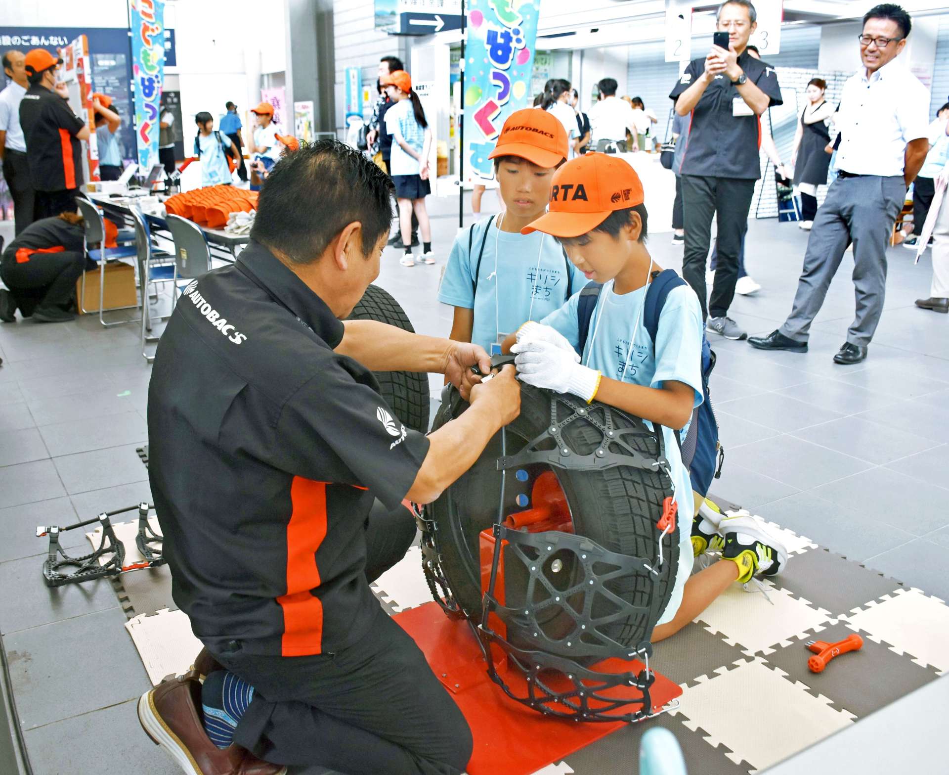 タイヤのチェーン付けを体験する子どもたち＝霧島市役所
