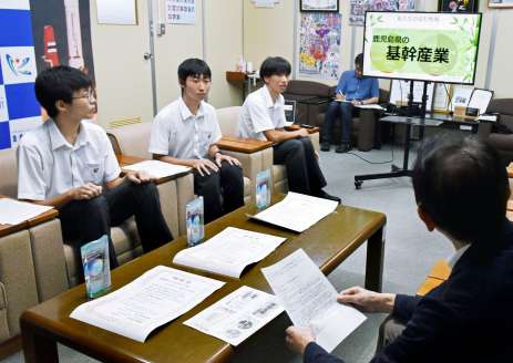 永野和行町長に受賞時のプレゼンを紹介する楠隼高校の生徒３人＝肝付町役場