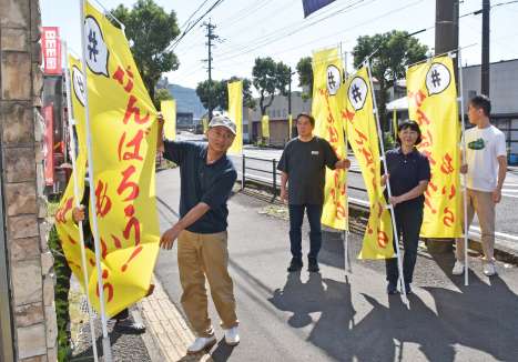 国道１０号沿いに黄色い旗を立てる網掛橋復興臨時通り会のメンバー＝７日、姶良市加治木