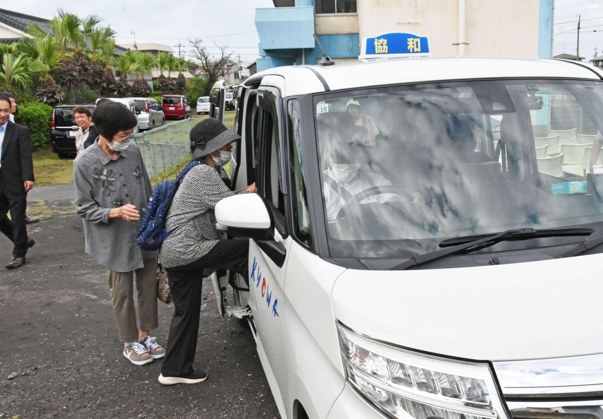 タクシーに乗り込む地元住民＝垂水市海潟の協和地区公民館