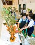 秋の花材を使い作品を仕上げる出品者ら＝８日、鹿児島市の山形屋