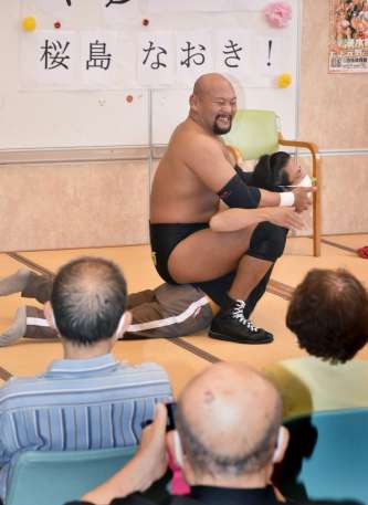 職員にキャメルクラッチをかけ盛り上げる桜島なおきさん（左）＝湧水町のつつはの園