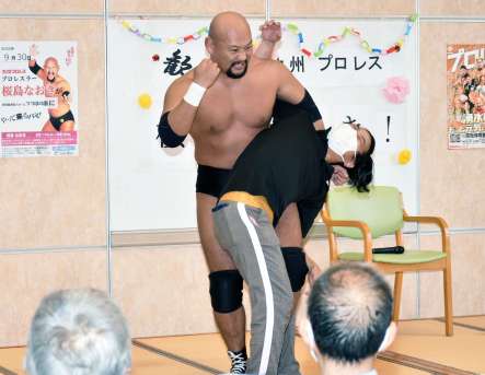 職員にコブラツイストをかけ盛り上げる桜島なおきさん（左）＝湧水町のつつはの園