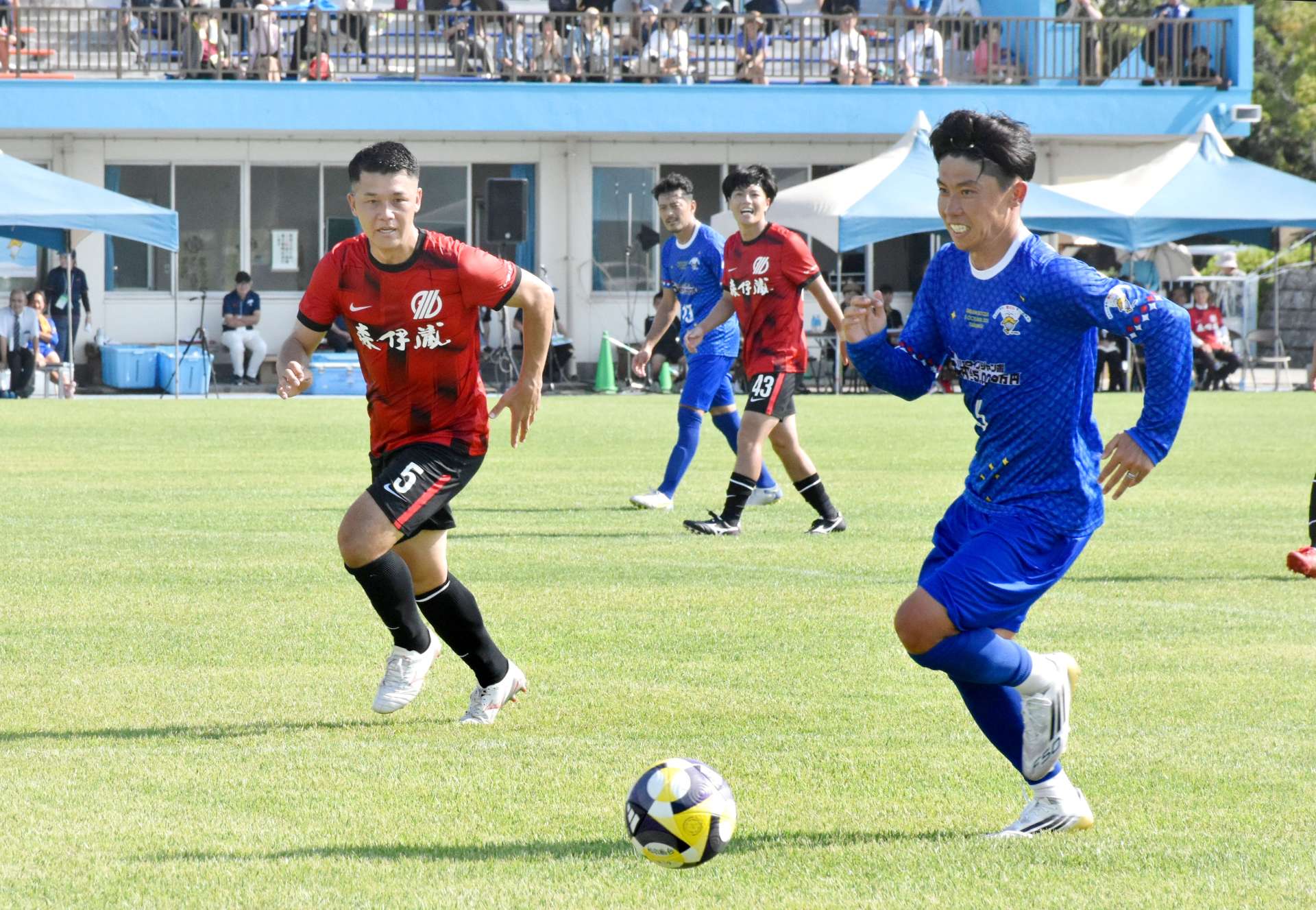 青いユニホーム姿で、垂水市選抜と親善試合をする日本代表ＯＢら＝同市の垂水中央運動公園