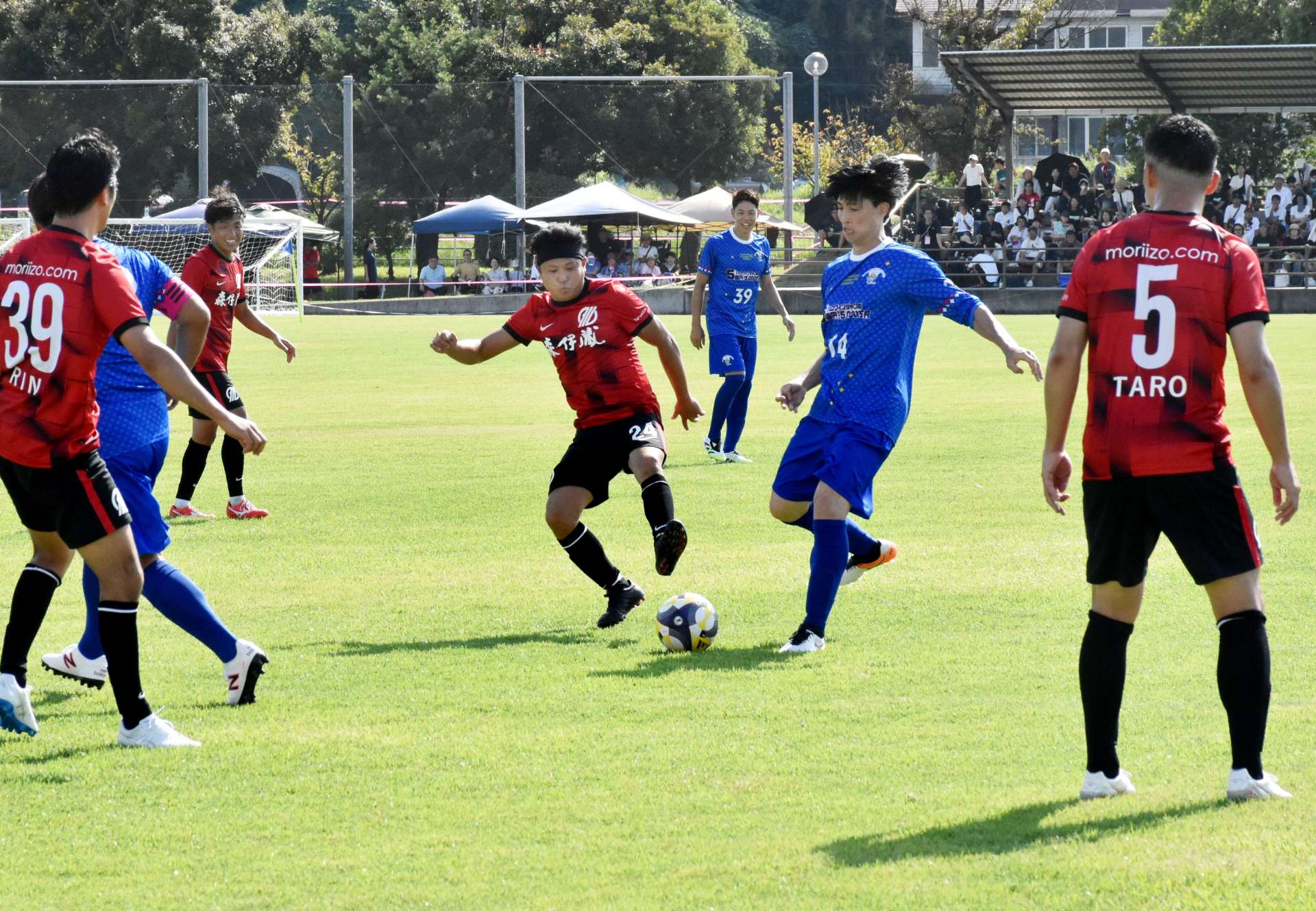 青いユニホーム姿で、垂水市選抜チームと親善試合をする日本代表ＯＢら＝同市の垂水中央運動公園
