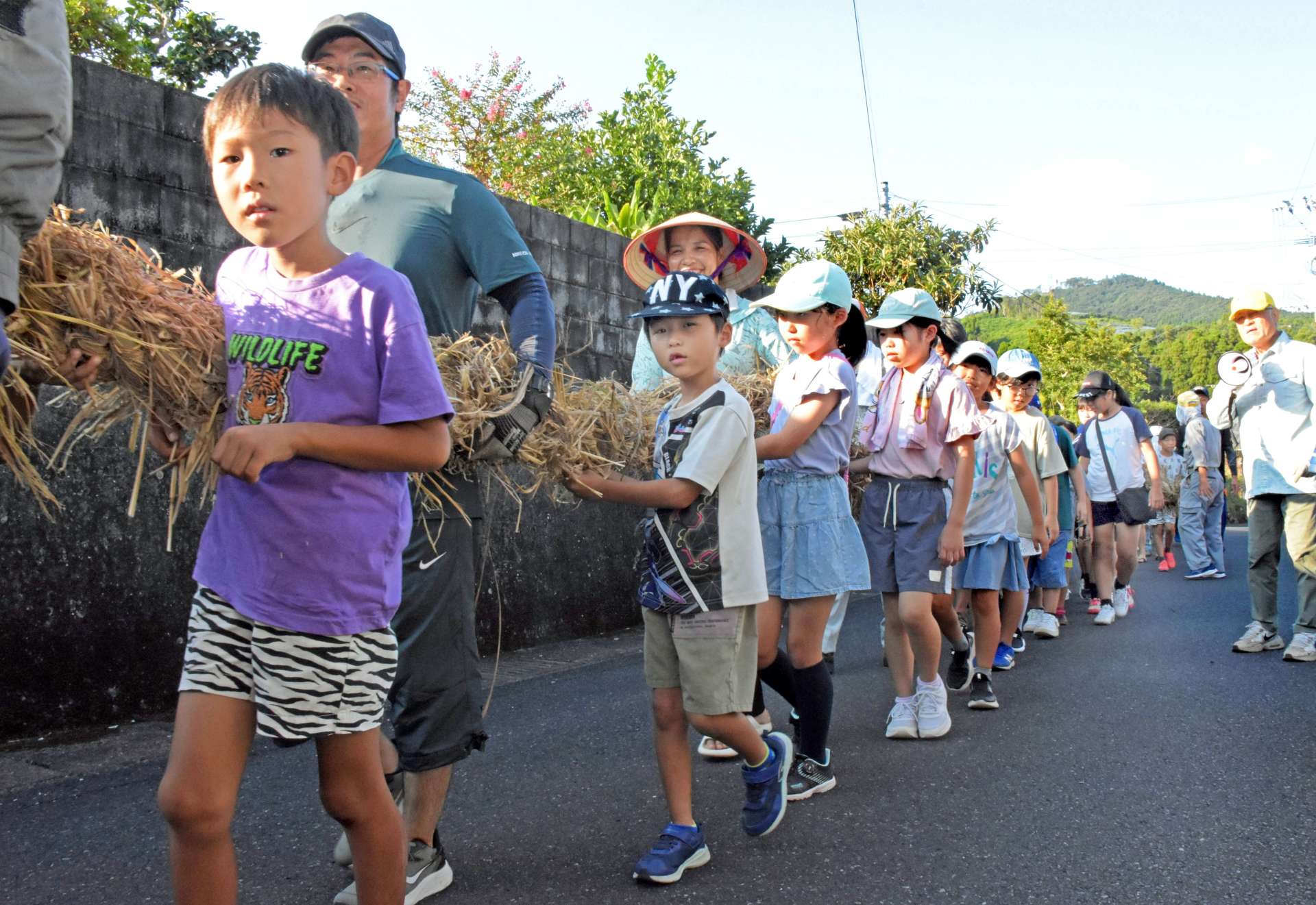 綱を担いで集落を練り歩く参加者＝５日、指宿市山川大山