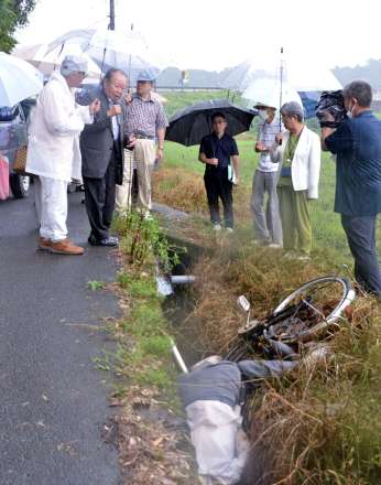 人形を使って、被害男性が自転車で側溝に転落した状況を再現する大崎事件弁護団＝１１日、大崎町井俣