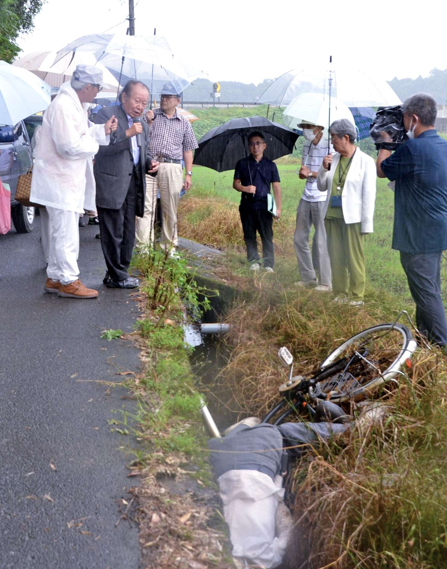 人形を使って、被害男性が自転車で側溝に転落した状況を再現する大崎事件弁護団＝１１日、大崎町井俣