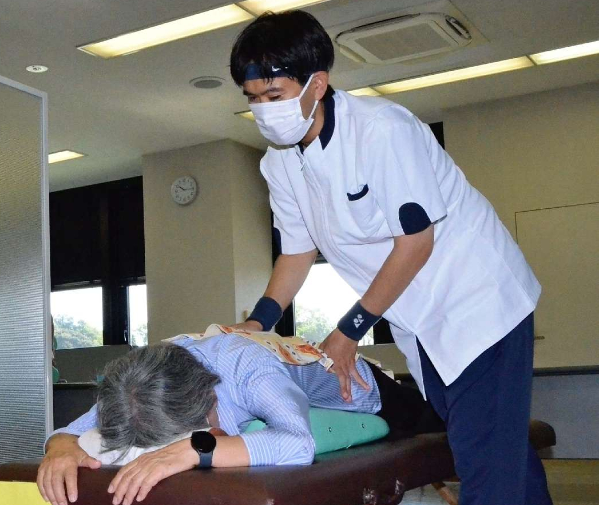 体の悩みを聞き、施術する鹿児島盲学校の生徒＝鹿児島市新照院町の城山ホテル鹿児島本社ビル